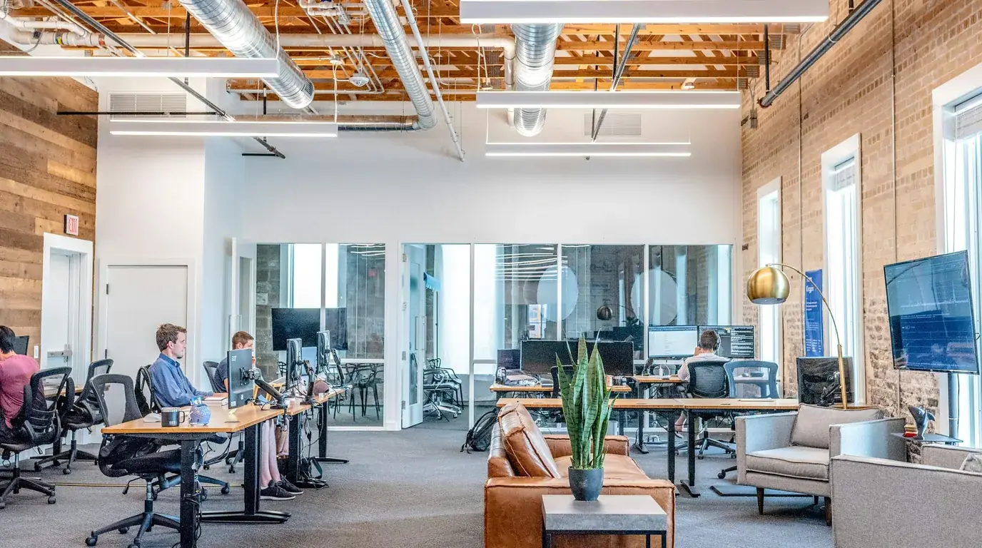 An open-plan office with timber ceilings, brick walls and rows of desks