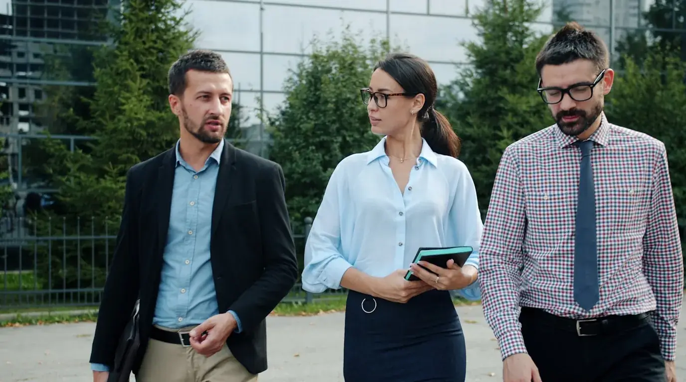 Three colleagues walking together outside a glass office building