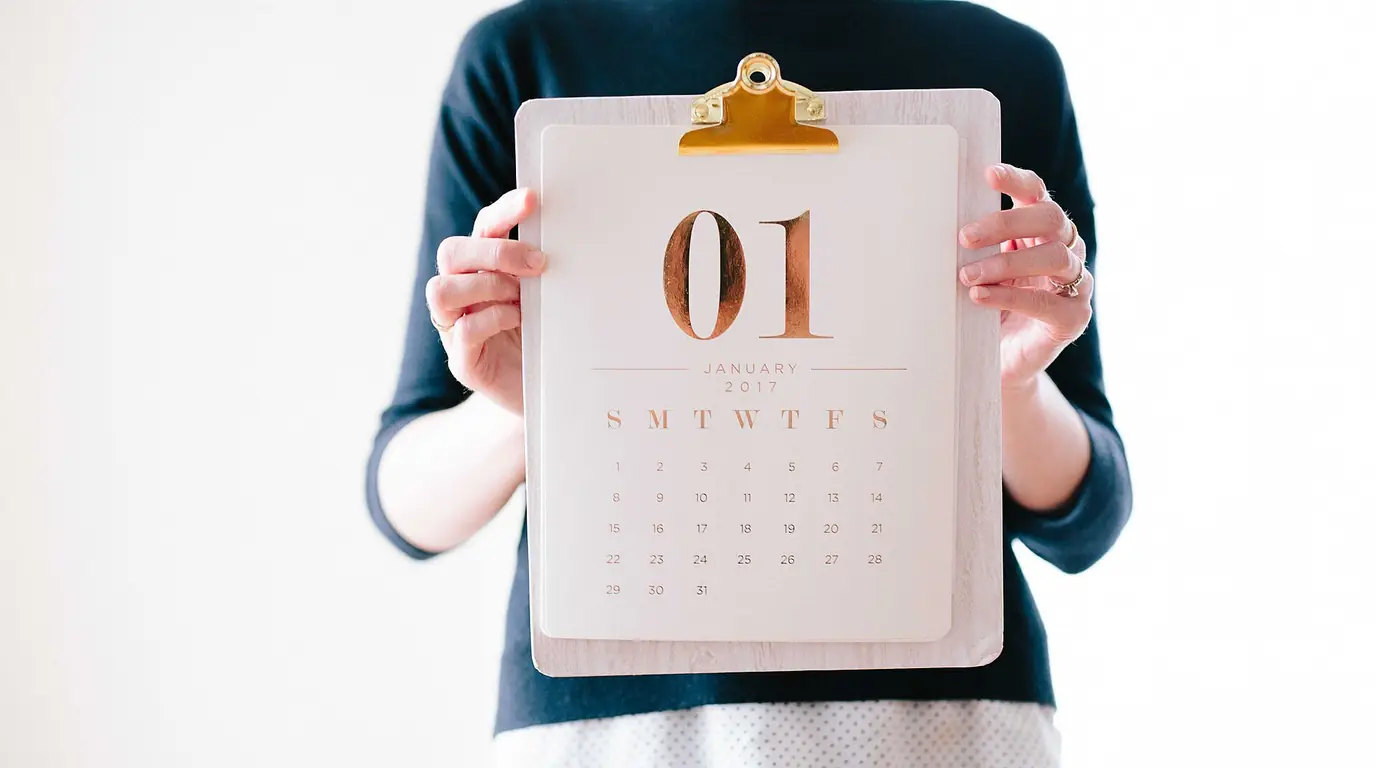 A person holding up a clipboard calendar page for January 2017 against a white background.